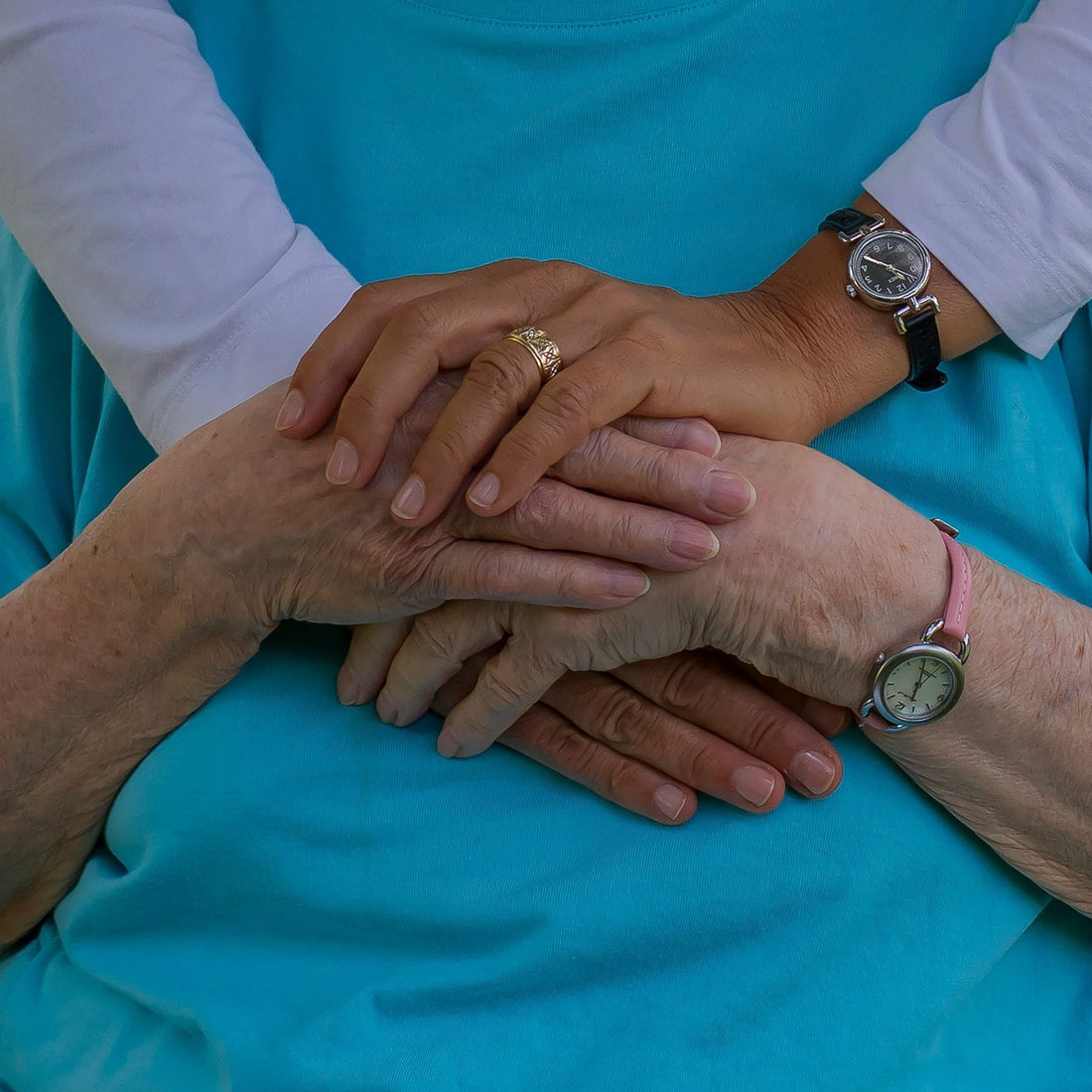 Adult caregiver helping an elderly woman organize prescription medications at a kitchen table