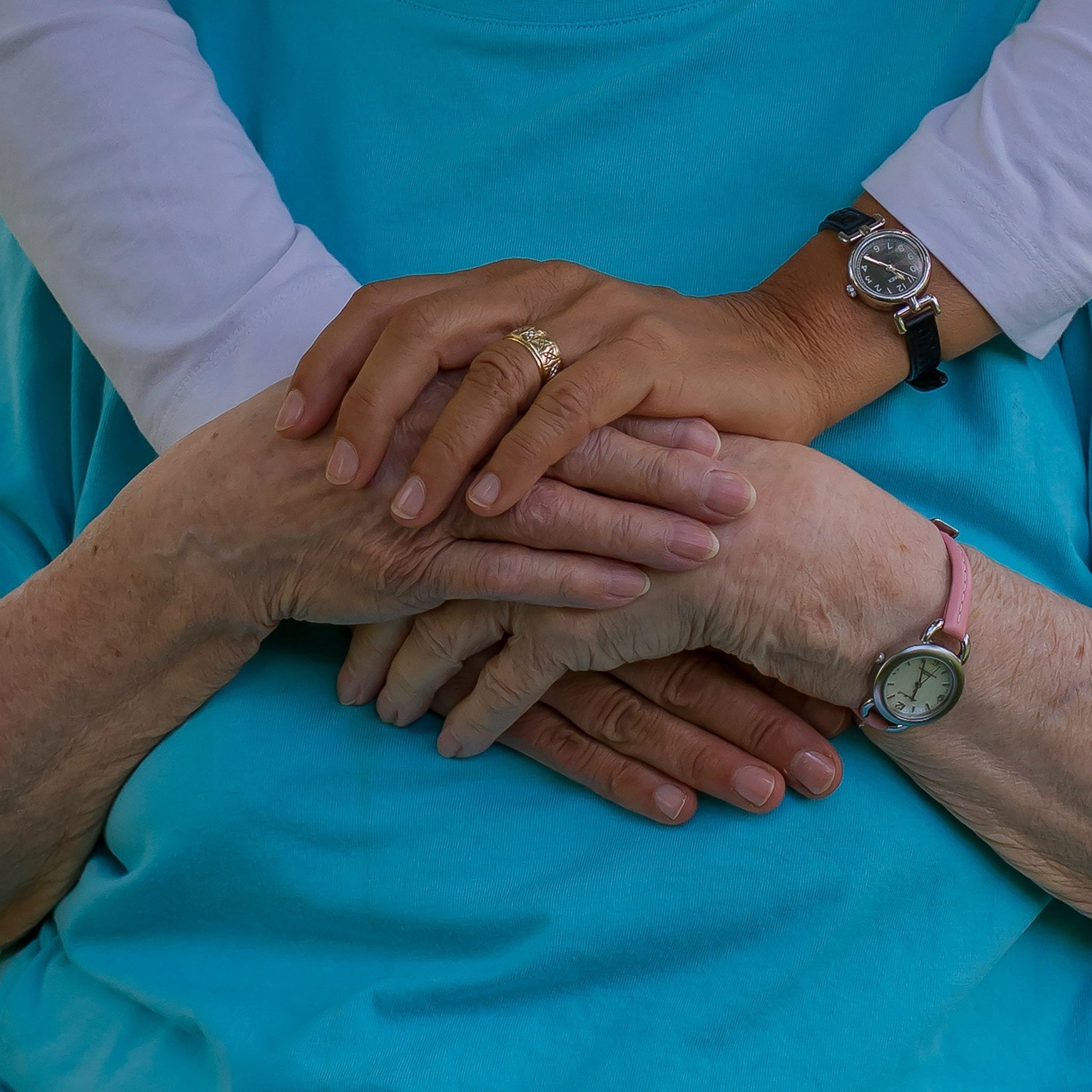 Adult caregiver helping an elderly woman organize prescription medications at a kitchen table